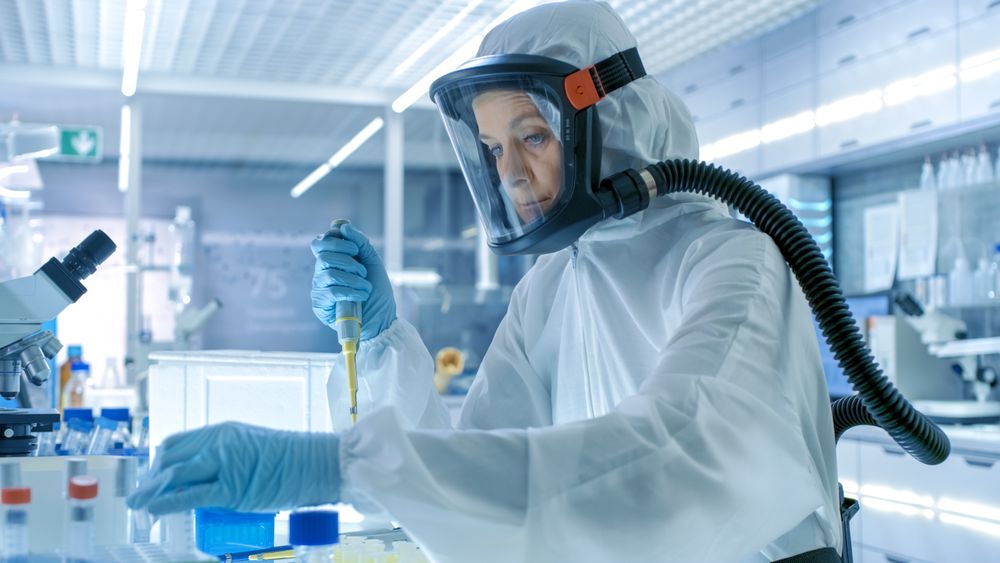 Medical Virology Research Scientist Works in a Hazmat Suit with Mask, She Takes out Test Tubes from Refrigerator Box.