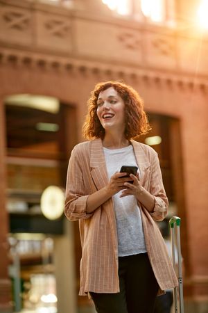 Red haired young woman using smartphone at station