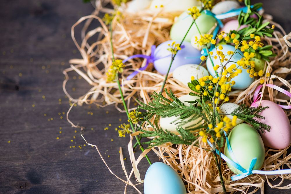 Easter holiday card concept with pastel eggs in hay on wooden table