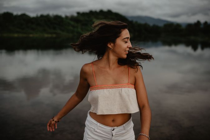 Cheerful woman dancing near lake