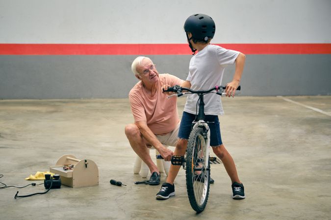 Grandfather with anonymous boy repairing bicycle