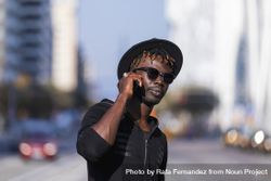 Black man wearing hat & sunglasses standing on the street talking on cellphone 4MGAEk