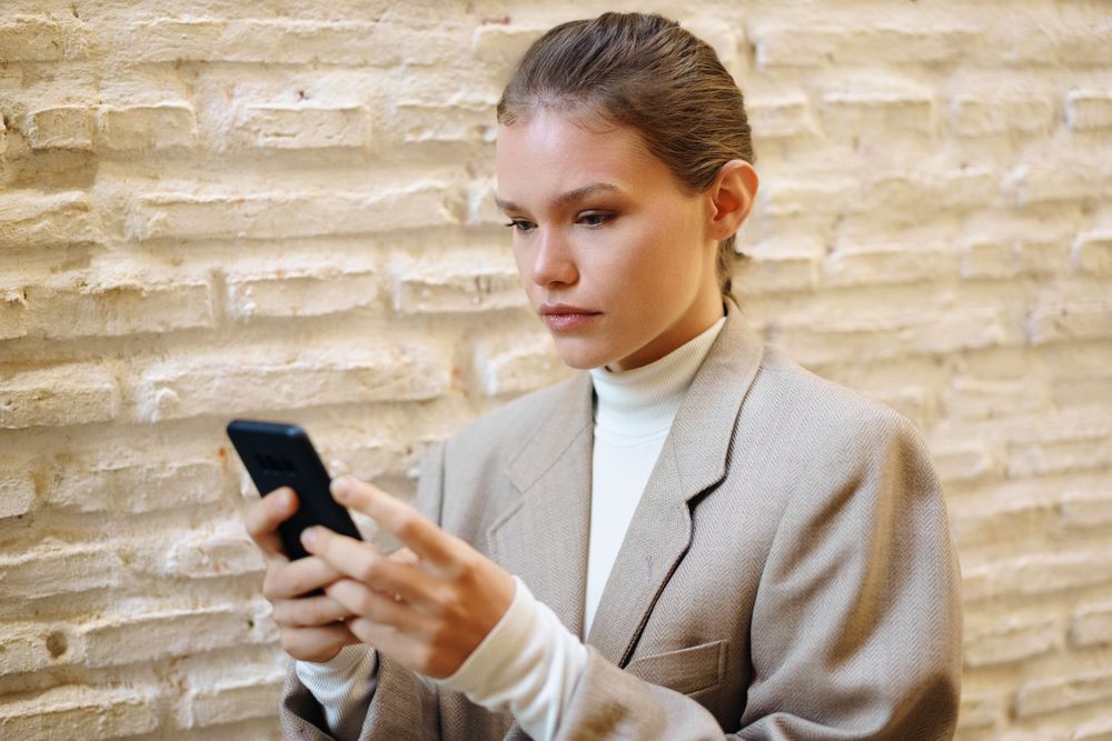 A focused young woman is fully engaged with her smartphone while in a modern and vibrant setting