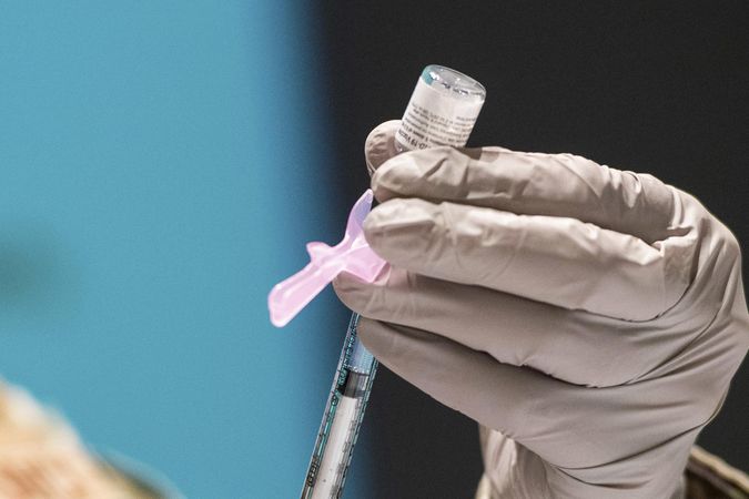 A technician loads a syringe with the COVID-19 vaccine