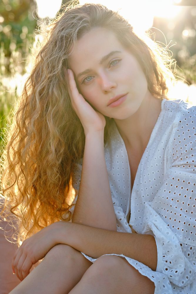 Woman touching cheek in sunny summer park