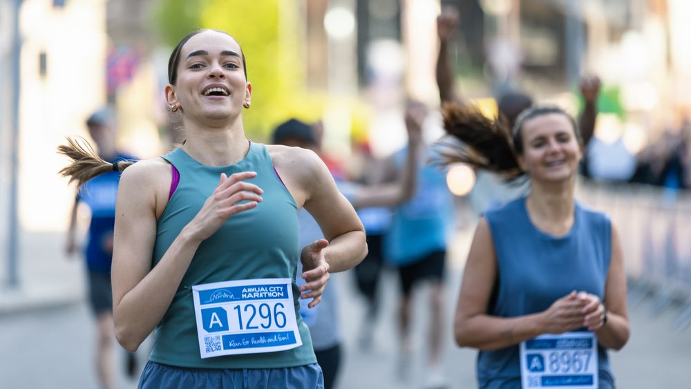 Active and Fit Smiling Female Runner Competing to Reach the Finish Line, Supported by Friends and Family