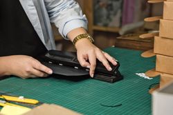 Hands of woman using sharp knife when cutting paper for making notebook