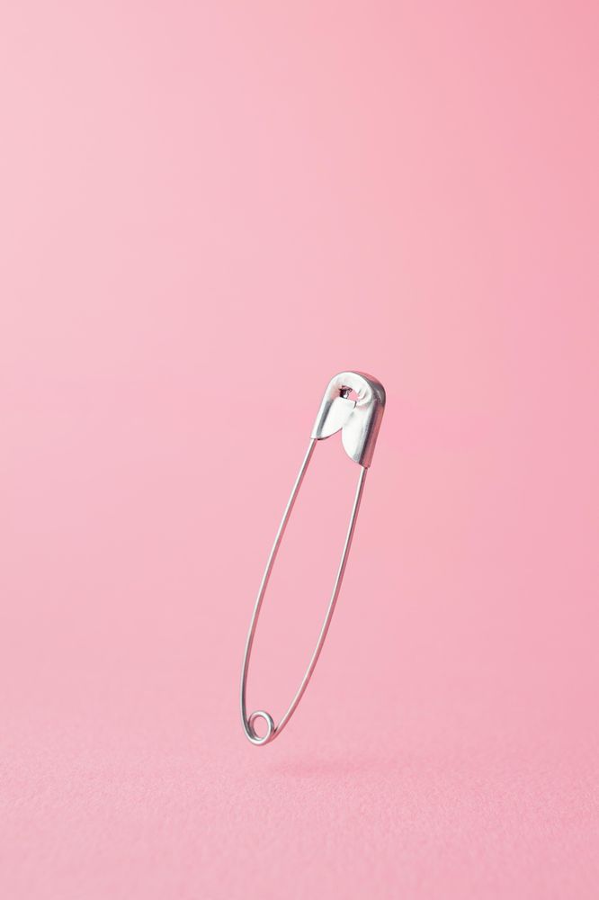 Close up of one safety pin on pink background