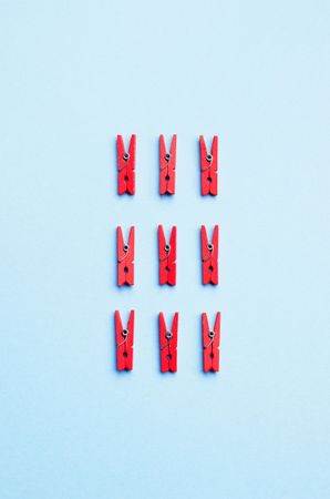 Red clothes pins on light blue background