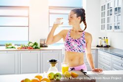 Athletic woman sipping water in bright kitchen 5RwG14