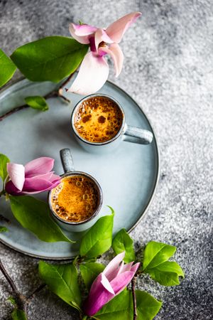 Coffee and magnolia flowers on grey concrete