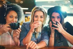 Multi-ethnic group of trendy girlfriends sipping coffee