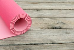 Yoga mat on wooden background, space for text
