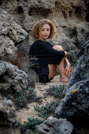 Young woman sitting between stones