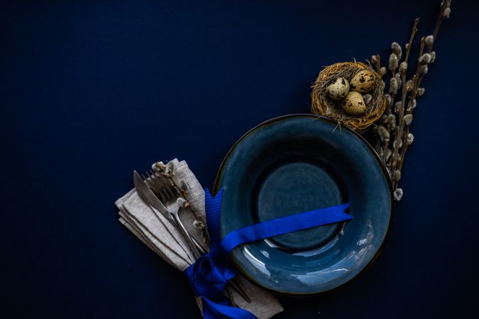 Top view of blue table and plate with bird's nest for Easter themed table setting