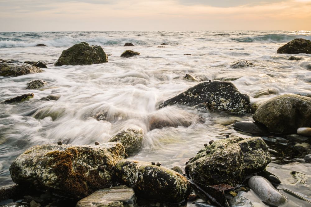 Stony seashore and waves at beautiful sunset