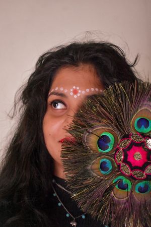 Portrait of Indian woman with Tilaka on forehead beside peacock feather