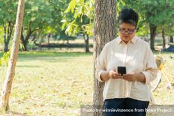 Mature Asian woman checking smart phone in park 5plJw5