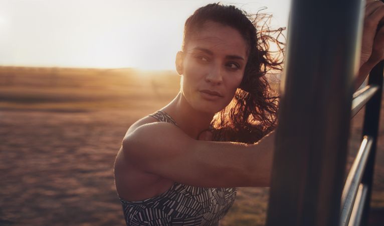 Close up portrait of determined young woman standing on the beach and looking away during evening