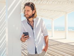 Relaxed man using smartphone in gazebo on beach