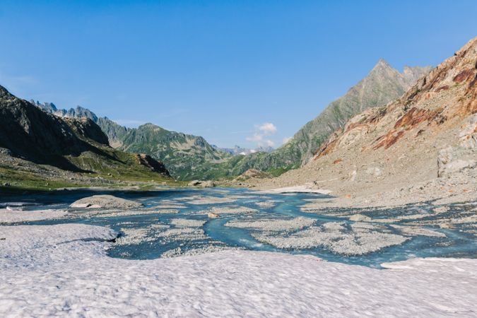 Shallow river flowing along rocky shore in bright day