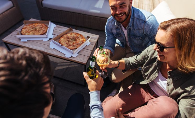 Group of millennial having drinks & pizza at rooftop party