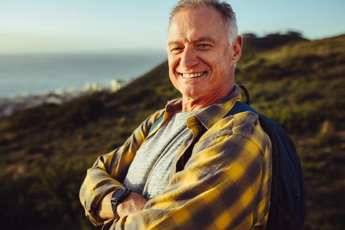 Portrait of a happy mature man standing with his arms crossed outdoors