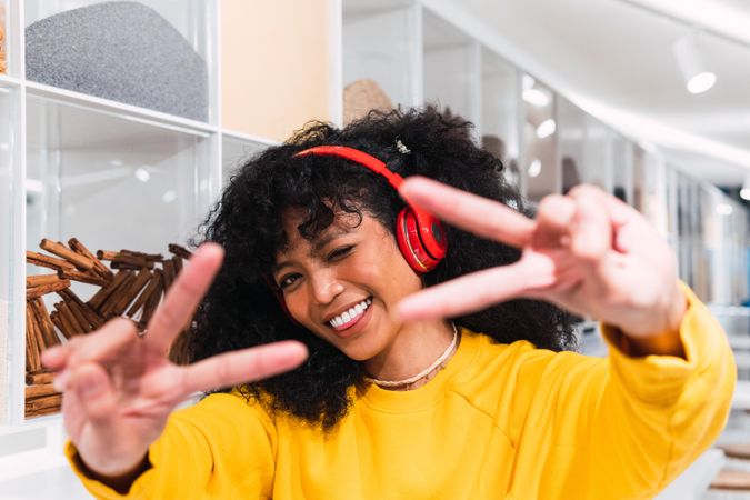 Carefree Black woman in headphones showing victory sign