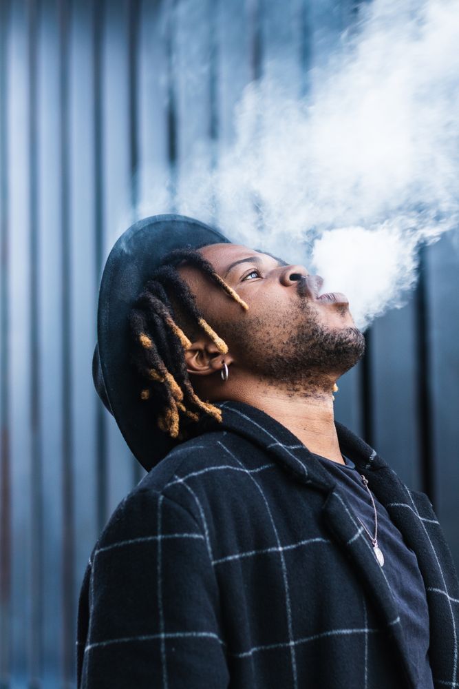 Black man exhaling cloud of smoke on street