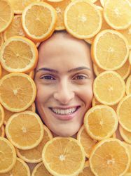 Smiling woman among slices of ripe oranges