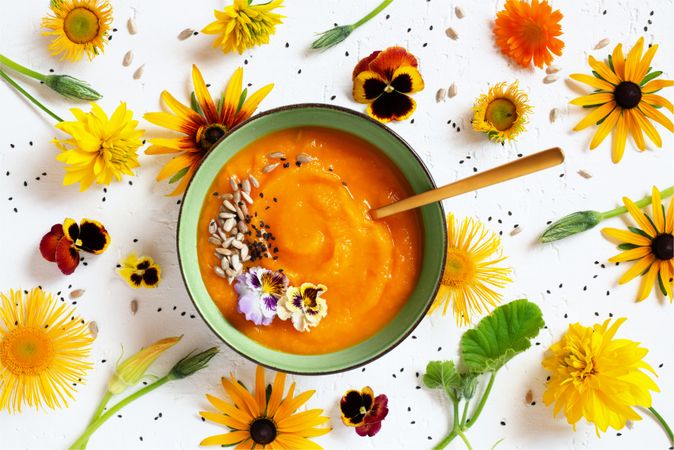 Top view of pumpkin soup with flowers on the table