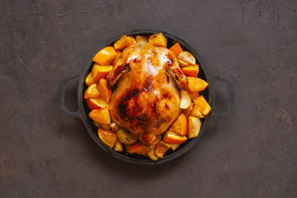 Chicken pot cooked with oranges on dark brown table