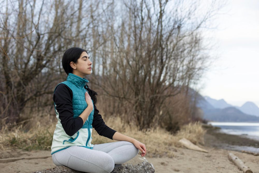 Calm young female sitting on a log while meditating