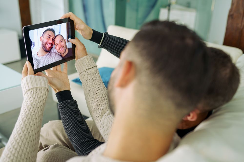 Male couple taking a selfie while relaxing on sofa