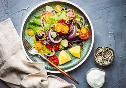 Fresh organic vegetable salad on counter with napkin and cutlery