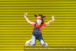 Cute child jumping in protective mask against a yellow wall 4jJav4