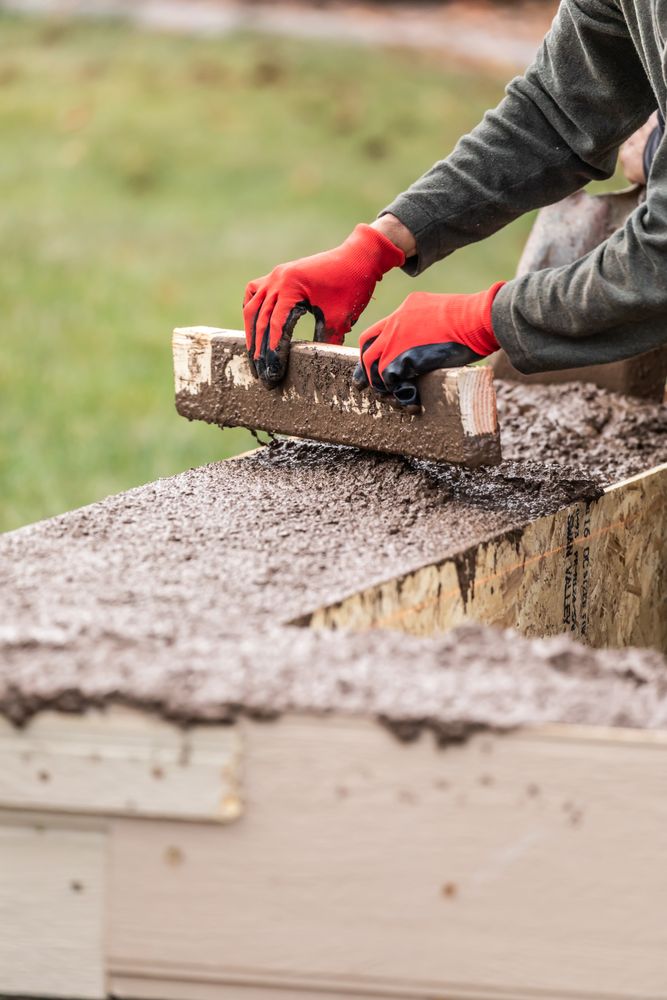 Construction Workers Pouring And Leveling Wet Cement Into Wood Framing