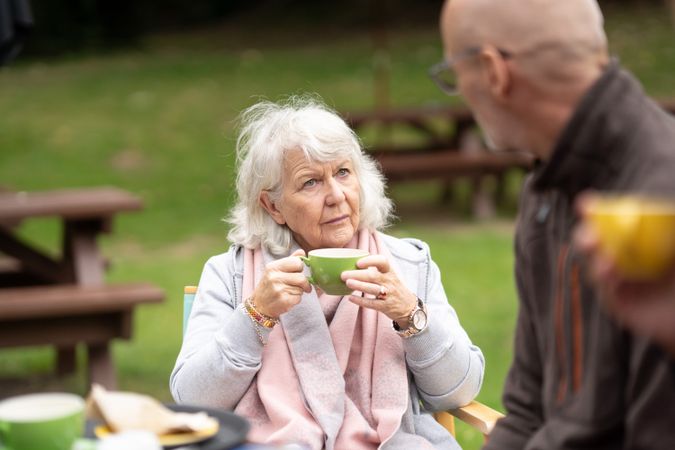 Woman enjoying tea while having a conversation with man