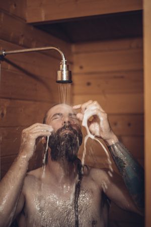 Man taking shower in wooden bathroom