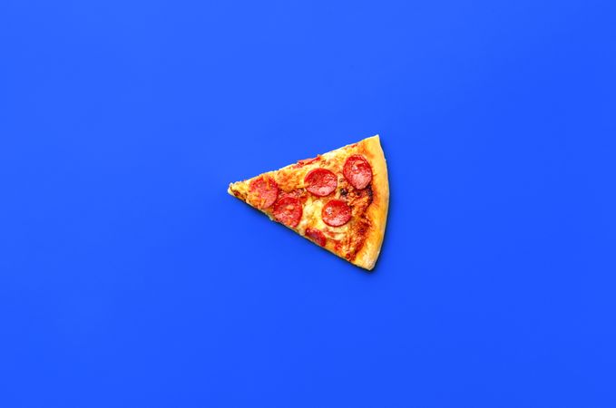 Slice of pepperoni pizza isolated on a blue background