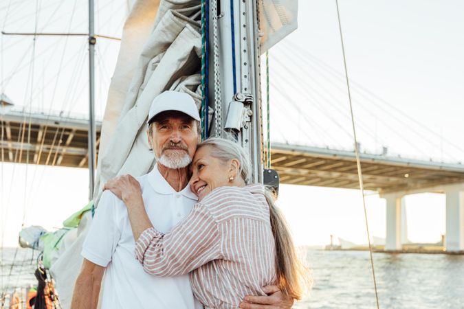 Mature couple holding each other as boat goes under a bridge