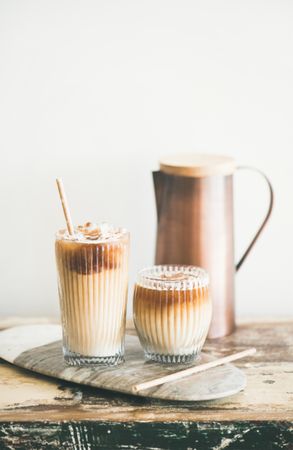 Two glasses of iced coffee with light background with pitcher