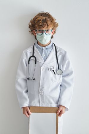 Boy in medical uniform with paper sheet and stethoscope