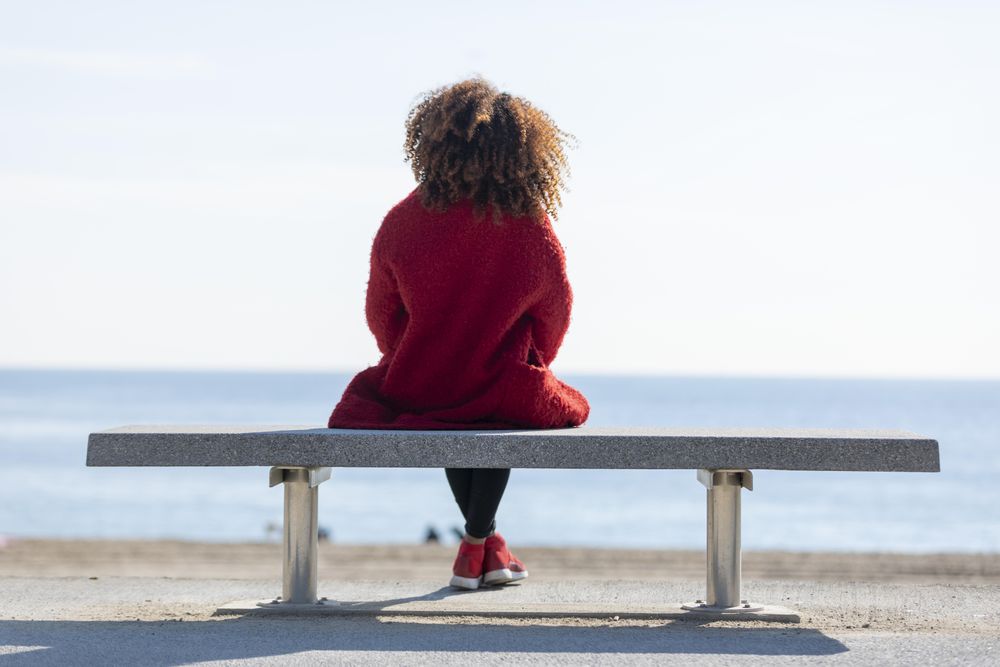 Back of calm woman enjoying view on seat overlooking the ocean