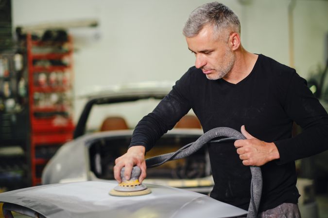 Mechanic grinding paint from car detail