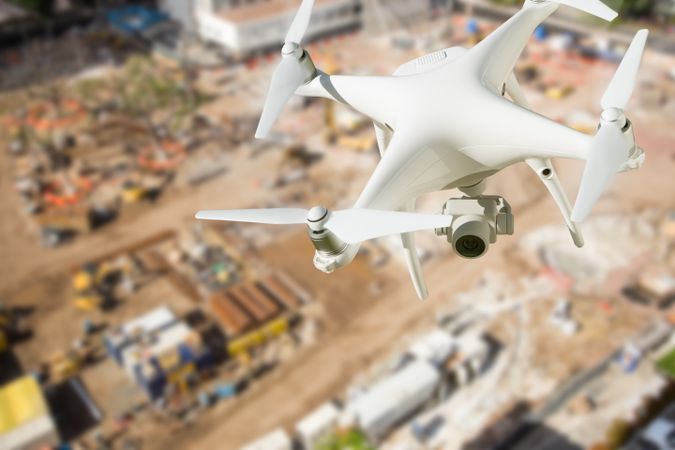 Unmanned Aircraft System (UAV) Quadcopter Drone In The Air Over Construction Site.