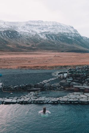 Woman in water near stones and hill