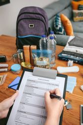 Woman doing checklist of emergency backpack
