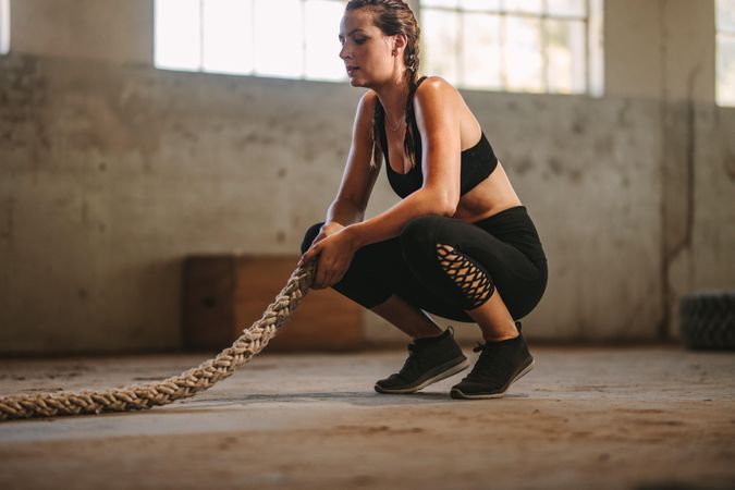 Fitness woman sitting on floor with battle rope