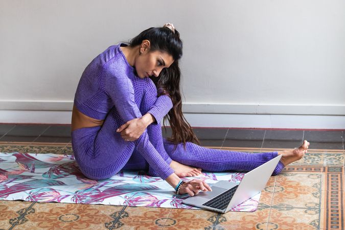 Brunette woman using laptop during yoga training at home
